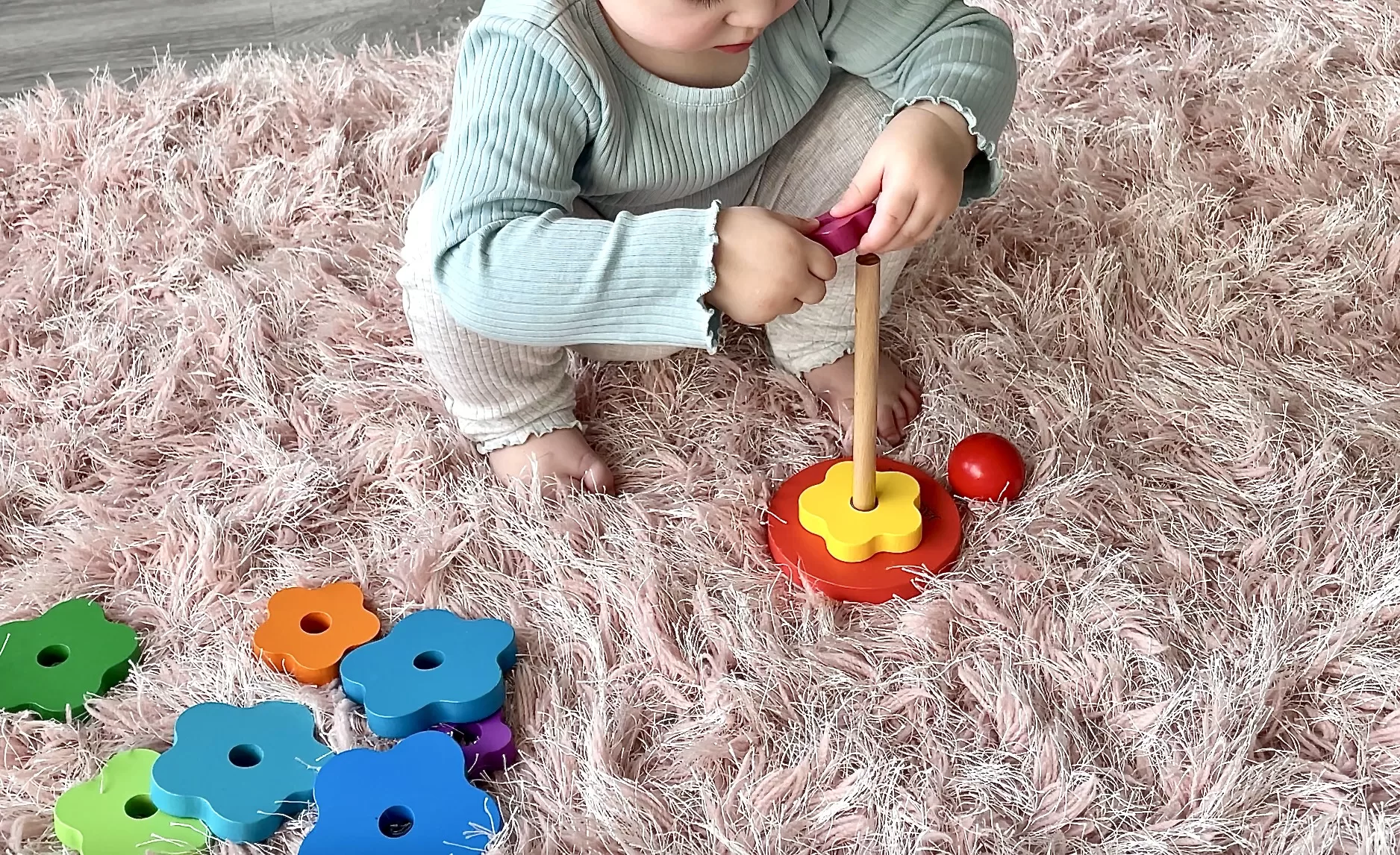 Toddler playing with rainbow stacking toy
