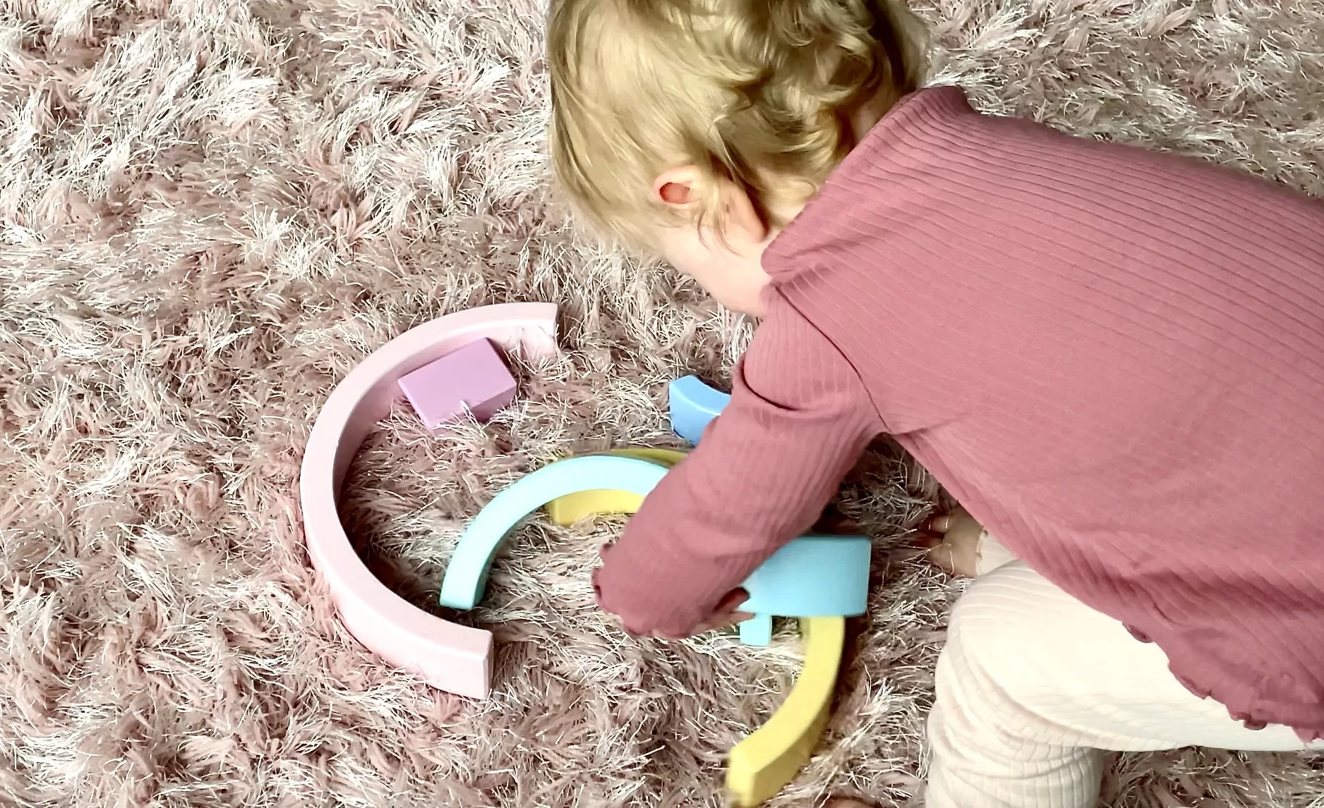 toddler playing with wooden rainbow stacker toy